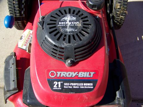 2000 Jeep Wrangler - A red Troy-Bilt self-propelled mower is shown from a close-up angle, highlighting its engine and deck.