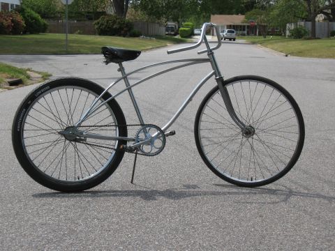 1994 Ford Bronco - A silver cruiser bicycle with a distinctive frame and wide handlebars is parked on an asphalt road.
