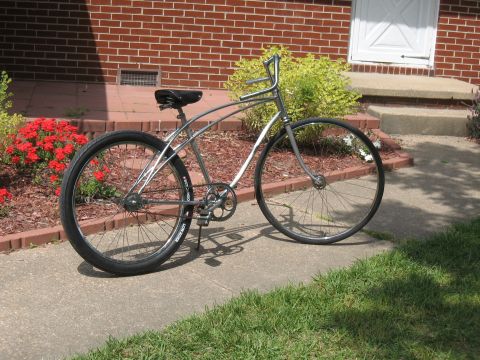 1994 Ford Bronco - A bicycle with a chrome frame and black tires is parked on a concrete path in front of a brick building.