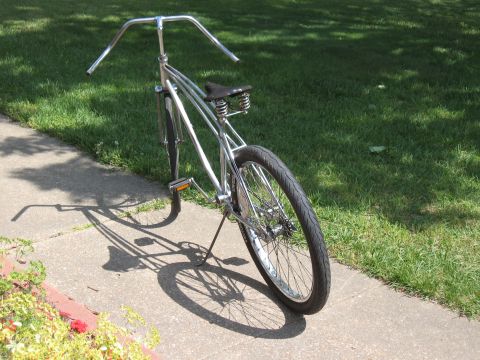1994 Ford Bronco - A custom cruiser bicycle with a chrome frame and wide handlebars sits on a sunny sidewalk.