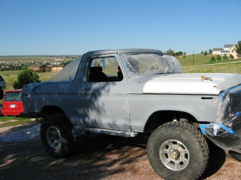1978 Ford Bronco - Ford Bronco undergoing prep work for a new paint job, with a red vehicle visible behind it.