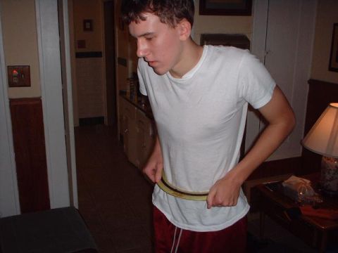 1996 Ford Taurus - A young man adjusts his belt while standing indoors.