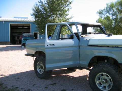 1978 Ford Bronco - Side view of a 1978 Ford Bronco undergoing restoration, with another vehicle visible in the garage.
