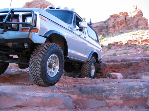 1978 Ford Bronco - This lifted 1978 Ford Bronco navigates a challenging rocky trail in a desert landscape.