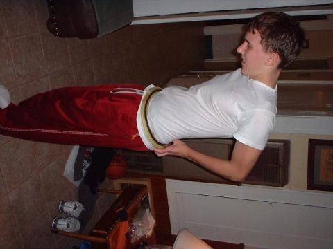 1996 Ford Taurus - A man is indoors holding a circular object while wearing red pants and a white t-shirt.