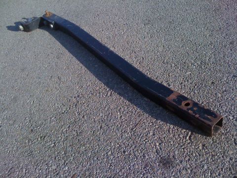 1986 Yugo GV - A black tow hitch part lies on a textured asphalt surface.