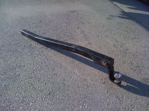 1986 Yugo GV - A black tow hitch with a ball mount rests on a textured asphalt surface.