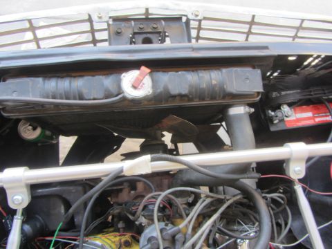 1964 Ford Ranchero - Close-up view of a vehicle's engine bay, showing the radiator, fan, and battery. A soda can is tucked near the radiator.