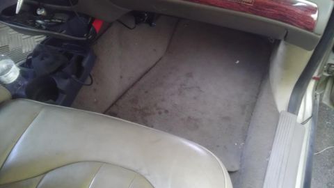 2000 Mercury Grand Marquis - The passenger side floor of a vehicle shows dirt and some items on the carpet.