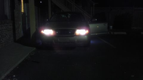 2000 Mercury Grand Marquis - The front of a Mercury Grand Marquis is visible at night with its headlights illuminated and the driver's door ajar.