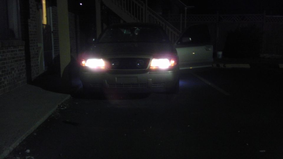 Front view of a 2000 Mercury Grand Marquis with headlights on and driver's door open