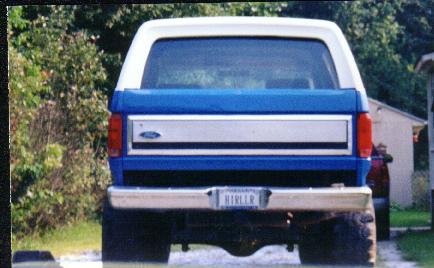 1985 Ford Bronco - Rear view of a blue and white 1985 Ford Bronco, showing its distinctive tailgate and taillights.