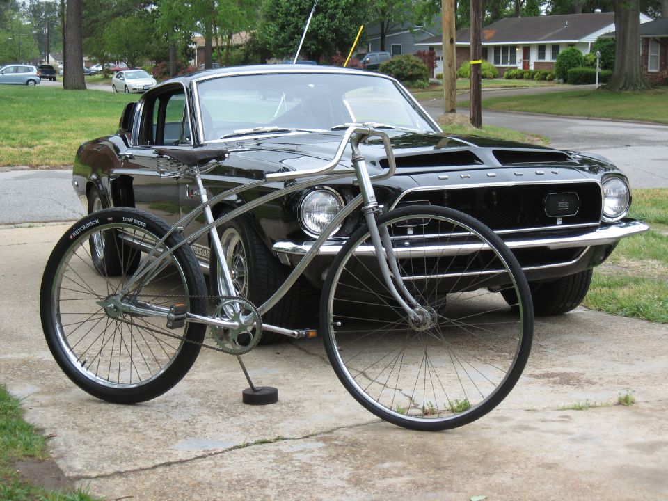 Black 1967 Ford Mustang parked behind a silver cruiser bicycle