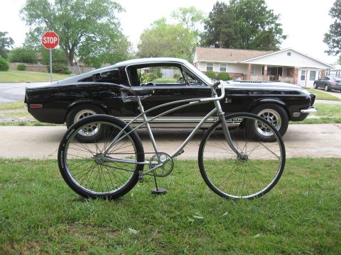 1994 Ford Bronco - A vintage bicycle is parked in front of a classic black muscle car on a suburban street.