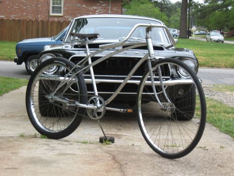 1994 Ford Bronco - A custom bicycle is parked in front of a vintage black car.