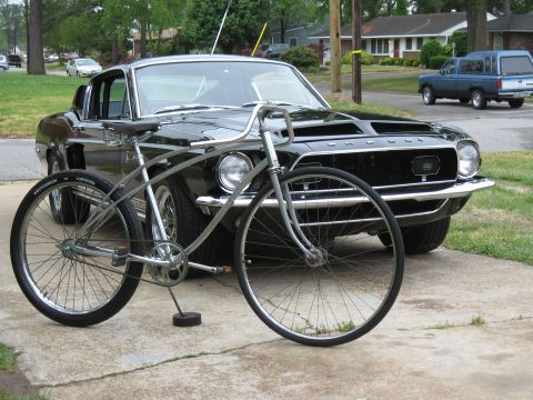 1994 Ford Bronco - A classic black 1967 Ford Mustang coupe is parked in front of a vintage bicycle.