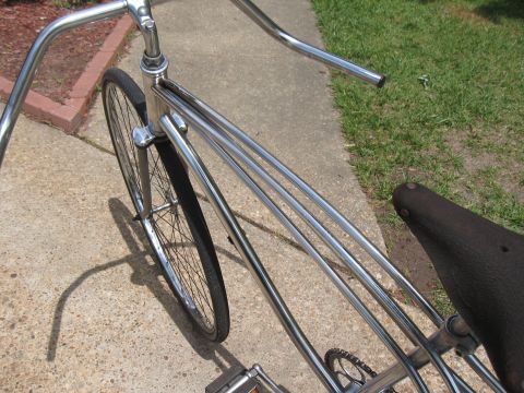 1994 Ford Bronco - A vintage-style cruiser bicycle with a shiny chrome frame and a dark leather seat is parked on a concrete path.