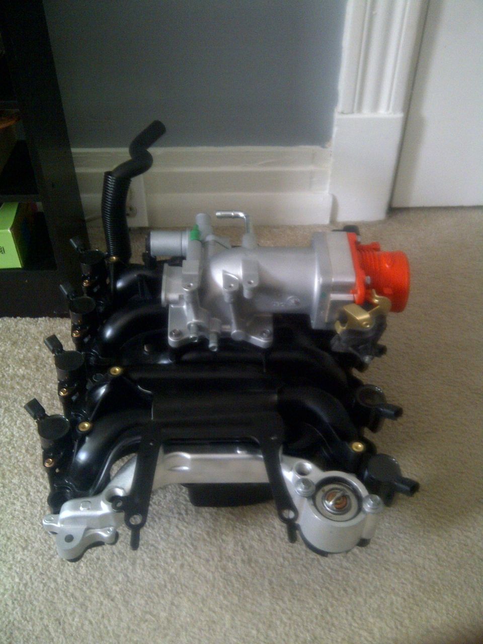Engine intake manifold with silver and black components, and an orange fitting