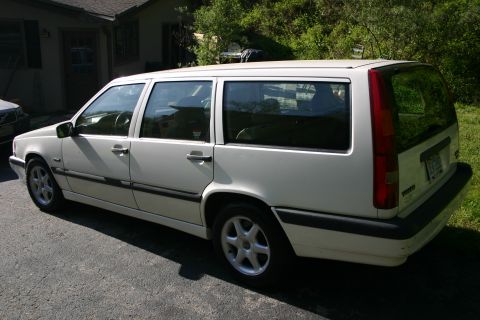 1997 Volvo 850 - A white 1997 Volvo 850 wagon is parked on an asphalt driveway in front of a house.