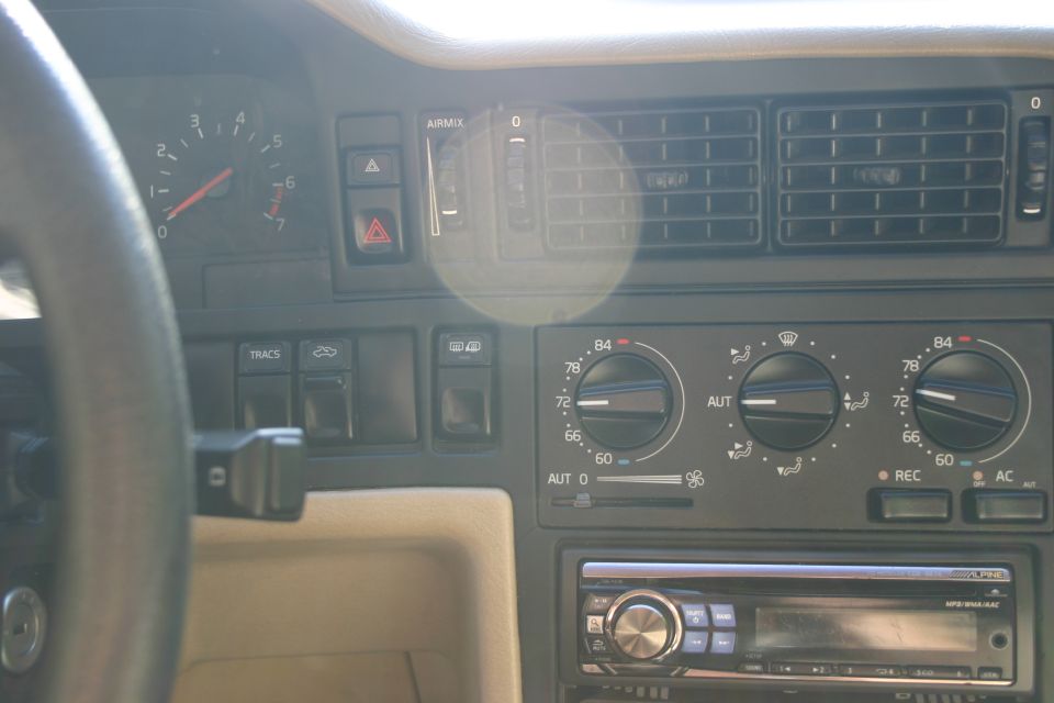 Car dashboard with tachometer, air vents, climate controls, and aftermarket stereo