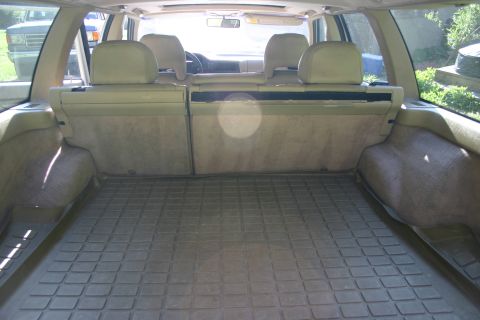 1997 Volvo 850 - The cargo area of a 1997 Volvo 850 wagon shows a rubber floor mat and folded rear seats, with another car visible outside.