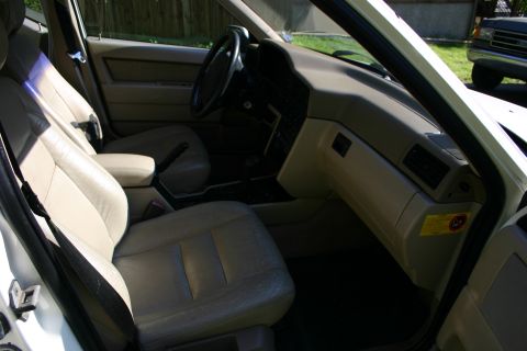 1997 Volvo 850 - Interior view of a 1997 Volvo 850, showing the front seats and dashboard. A truck is parked outside.