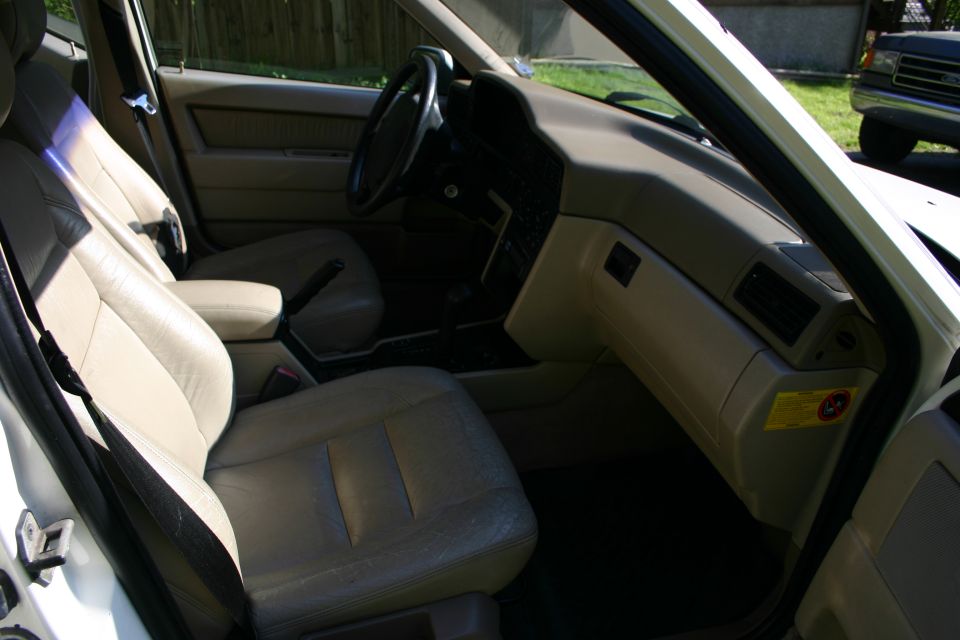 1997 Volvo 850 interior, beige leather seats, dashboard, and center console. Another vehicle is visible outside