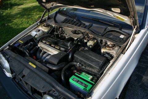 1997 Volvo 850 - The engine bay of a 1997 Volvo 850 is shown with the hood open, revealing the engine and battery.