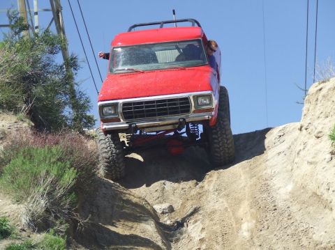 1978 Ford Bronco - This red 1978 Ford Bronco is captured mid-climb on a steep dirt incline, its off-road capabilities.