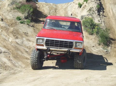 1978 Ford Bronco - This red 1978 Ford Bronco is captured mid-climb on a steep, dusty incline.