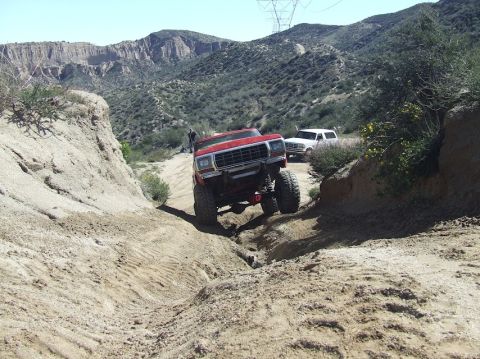 1978 Ford Bronco - Two SUVs navigate a challenging off-road trail in a mountainous, arid landscape.