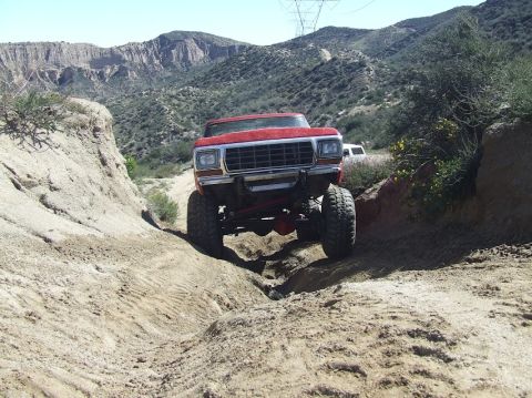 1978 Ford Bronco - A red 1978 Ford Bronco navigates a steep dirt path in a mountainous, arid landscape.