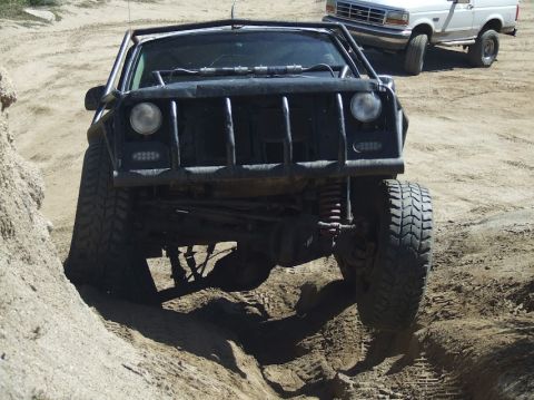 1978 Ford Bronco - A heavily modified SUV navigates a sandy, off-road trail with another vehicle visible in the distance.