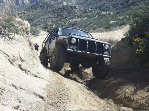 1978 Ford Bronco - An off-road SUV navigates a steep dirt trail with a custom front end and roll cage.