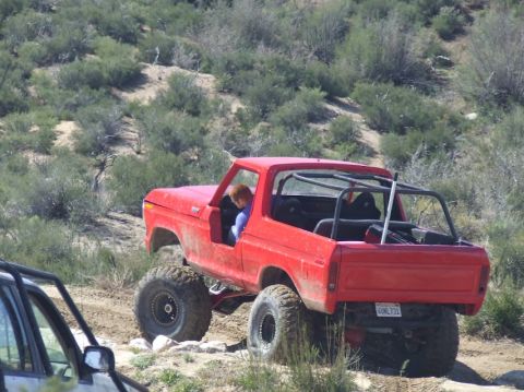 1978 Ford Bronco - This red SUV is modified for off-road use and is seen on a dirt path with sparse vegetation.