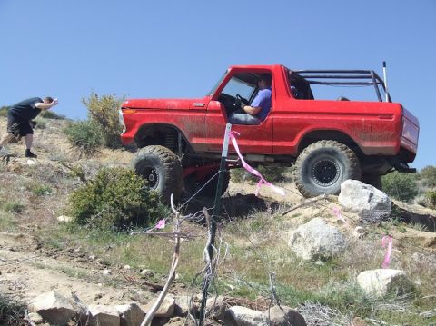 1978 Ford Bronco - A red 1978 Ford Bronco navigates a challenging off-road course with assistance from a spotter.