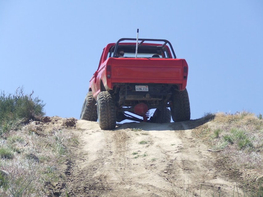 red pickup truck with roll cage climbing a dirt hill