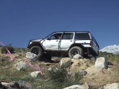 1978 Ford Bronco - This white SUV, equipped with a roll cage and off-road modifications, tackles a challenging rocky course.