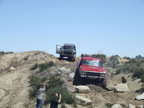 1978 Ford Bronco - Two off-road vehicles navigate a rocky incline under a clear blue sky.