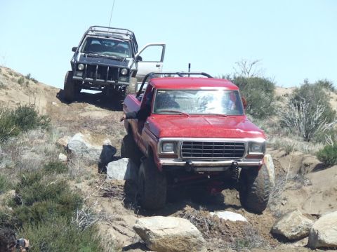 1978 Ford Bronco - A red 1978 Ford F-Series pickup truck navigates a rocky trail, followed by a black SUV.