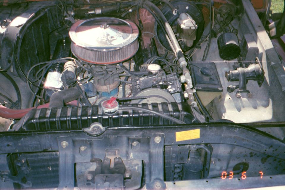 Engine bay with V8 engine and round chrome air cleaner, viewed from above the radiator support