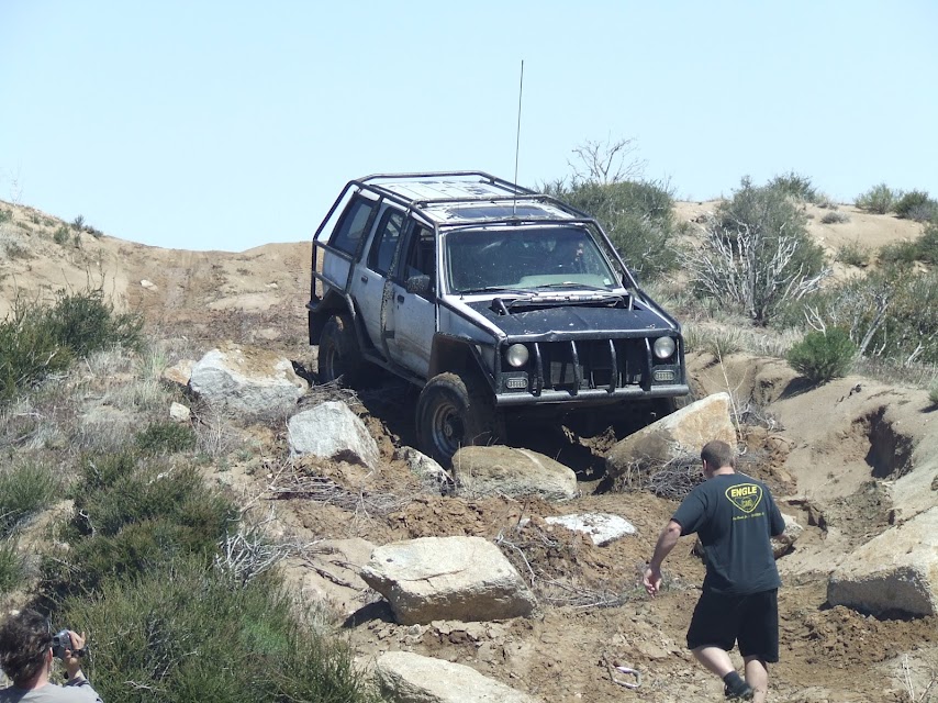 Jeep Cherokee XJ with a roll cage navigating a rocky trail