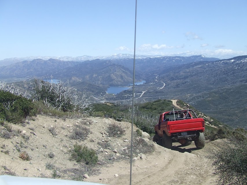 Red pickup truck with a roll bar driving on a mountain dirt road