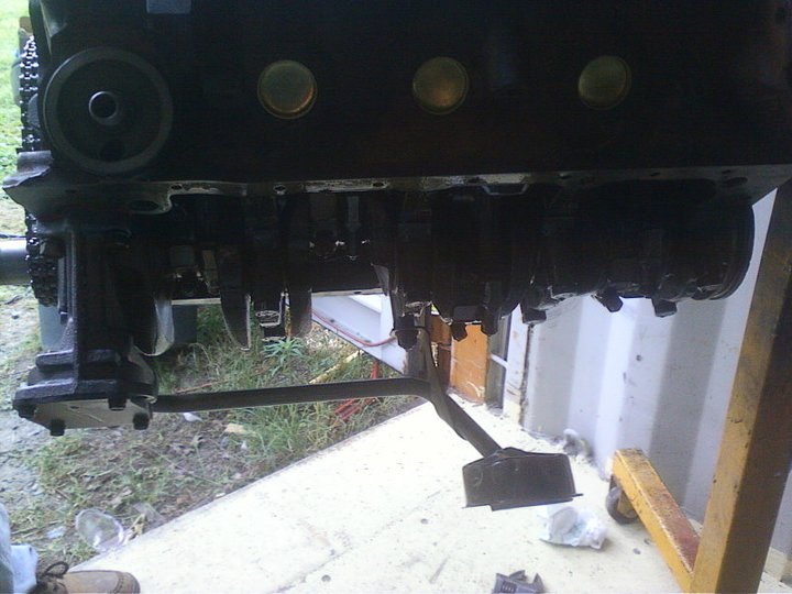Black engine block with exposed crankshaft and oil filter housing, supported by a yellow engine stand