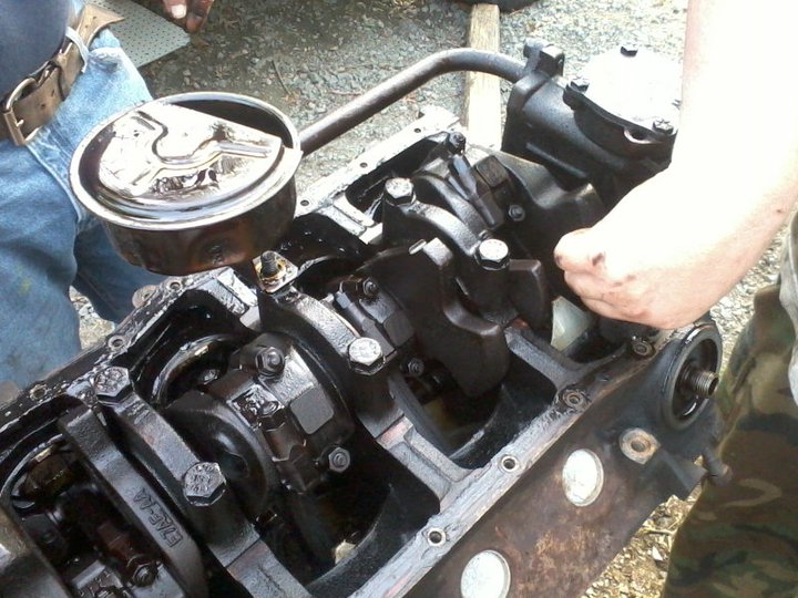 Engine block with crankshaft and connecting rods, partially disassembled, with a hand reaching in