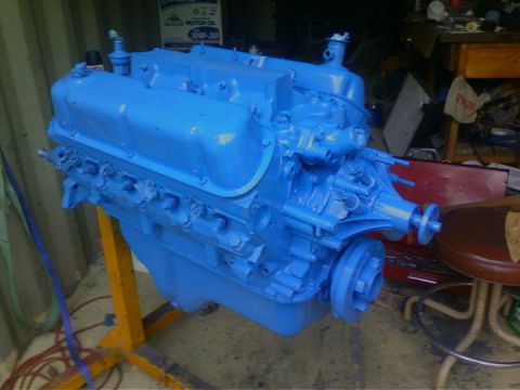 1989 Ford Bronco - V8 engine painted bright blue, mounted on an engine stand in a workshop.