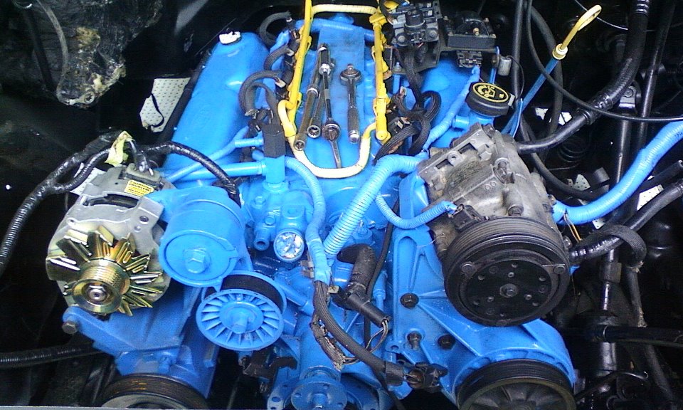 Engine bay with bright blue painted engine components, alternator, and AC compressor