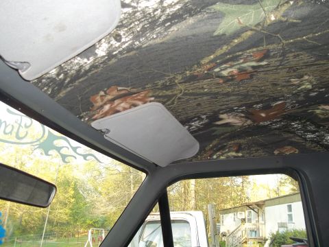 1989 Ford Bronco - Interior view of a vehicle with a camouflage headliner and sun visors, showing a side mirror and a glimpse of the exterior.