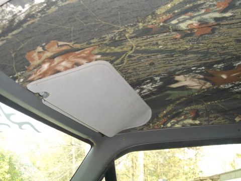 1989 Ford Bronco - The interior of a vehicle features a camouflage headliner and a light gray sun visor.