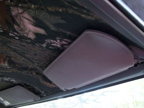 1989 Ford Bronco - The interior of a vehicle displays a camouflage headliner and gray sun visors, with "SUPERMOTORS" text visible on the lower right.